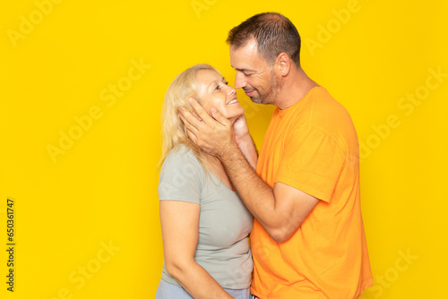 Caucasian loving couple about to kiss to show their love and respect for each other, isolated on yellow studio background. © Andres