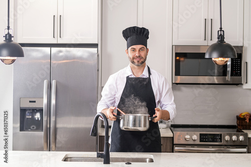 Male cook or chef cooking food in pan pot in kitchen. Process of preparing gourmet dish. Man cooking at home in kitchen, using pot. Chef cooking food. Handsome chef cook cooking concept. photo