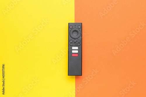 Modern TV remote control on a yellow-orange background. TV management concept.