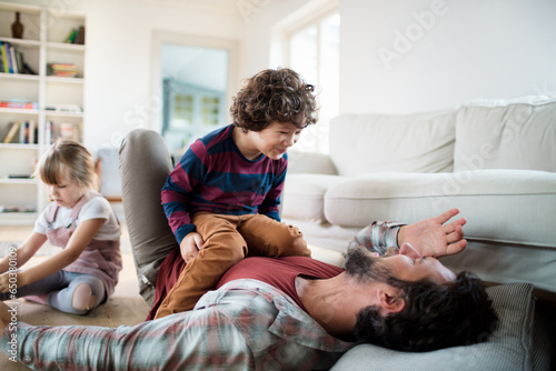 Young father playing with his son in the living room at home