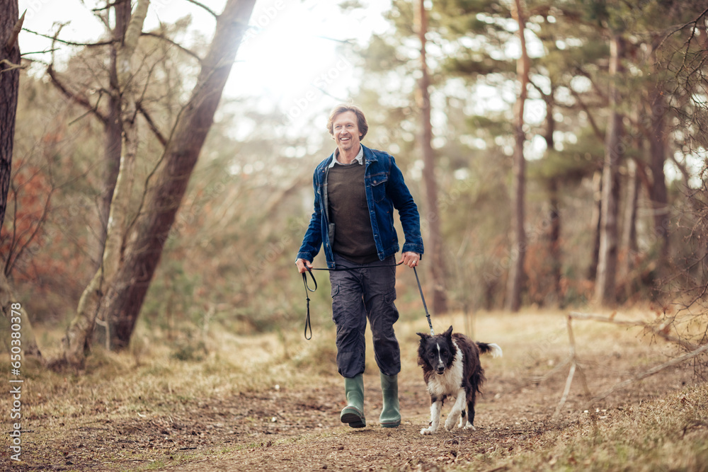 Middle aged man walking his dog through the woods Middle aged man walking his dog through the woods