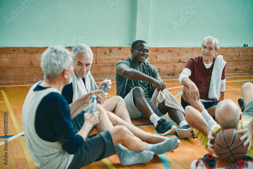 Diverse group of senior men taking a break from playing basketball in an indoor basketball gym