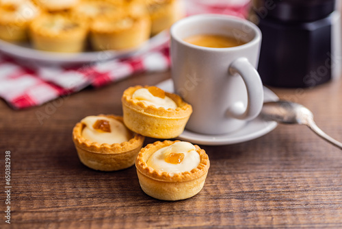 Sweet tarlets. Tasty mini tarts. Mini pie with cream and coffee cup  on kitchen table. photo