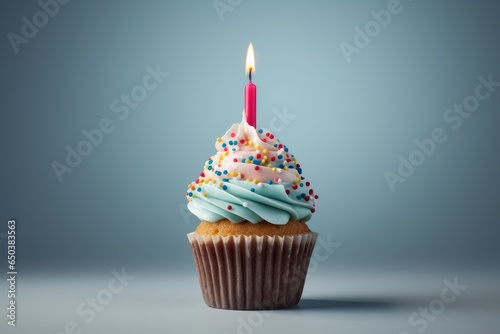 Festive muffin with white and blue cream and candle  blue background