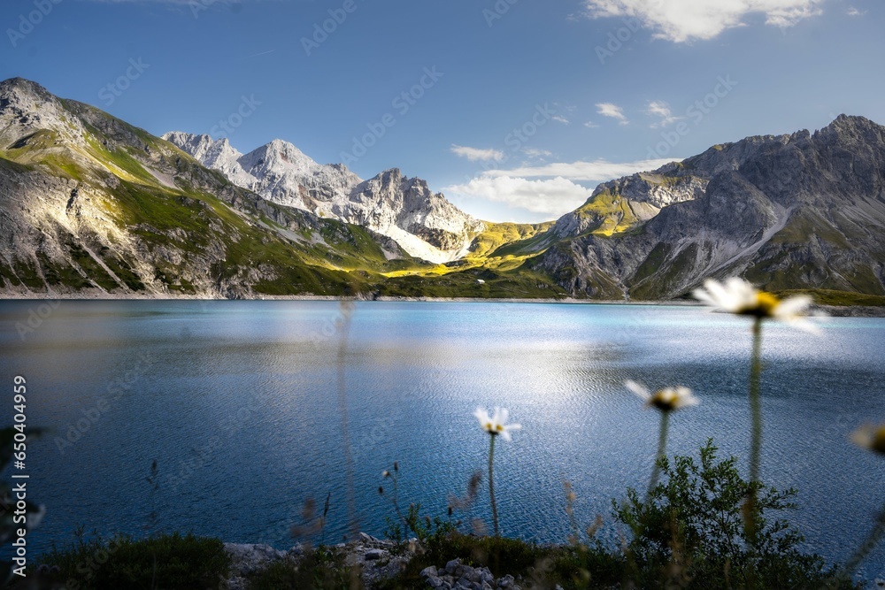 Tranquil Lunersee lake surrounded by lush green grass and jagged mountains in Austria