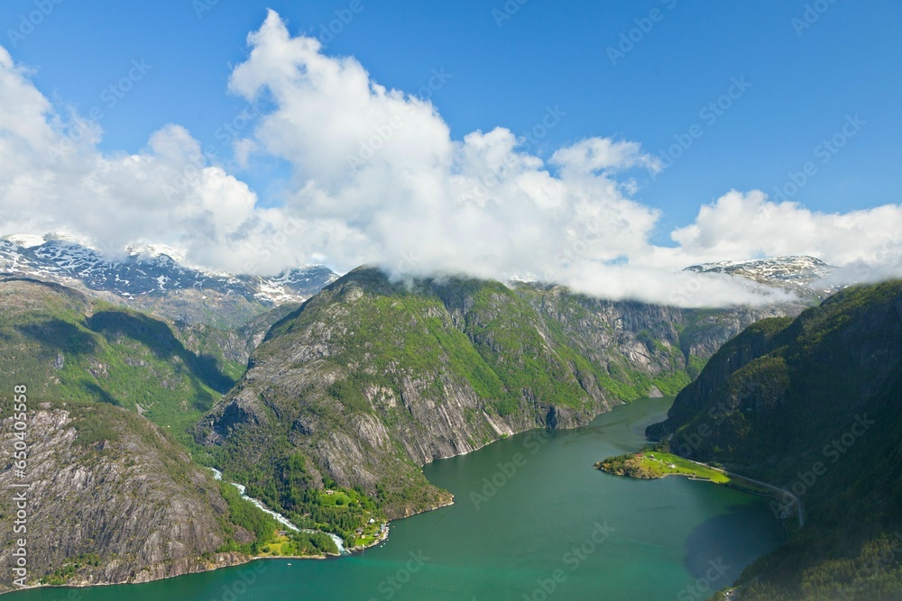 Lake surrounded by mountains with blue cloudy sky in the background