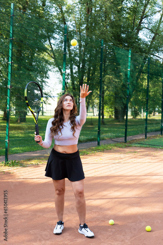 A woman athlete tennis player training with a racket and ball on the court. Vertical format.