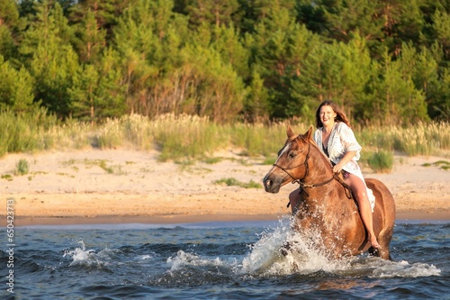 Young female having fun riding a horse through the shallow waters of a tranquil lake
