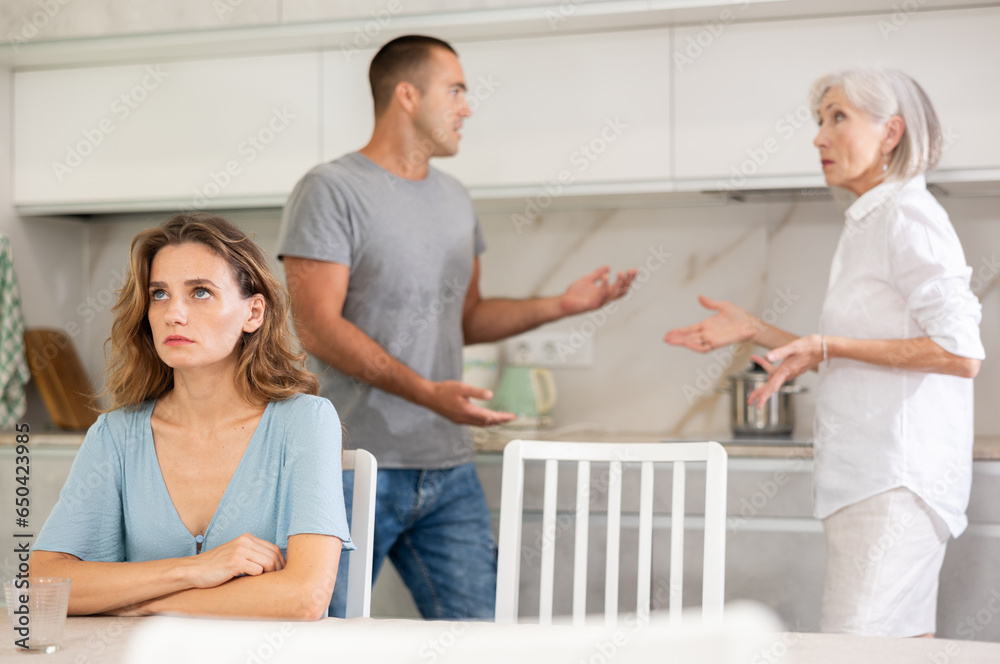 Obraz premium Family of three - mother-in-law, daughter and son quarreling in kitchen