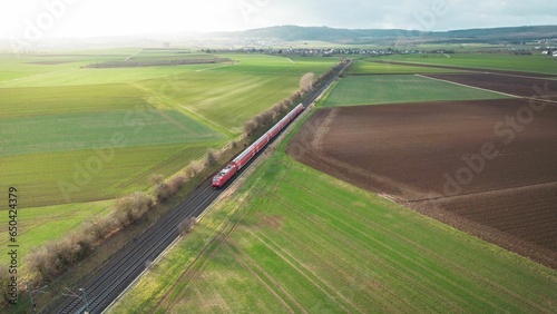 Drone view of a train on the tracks in a farm field on a sunny day in Germany