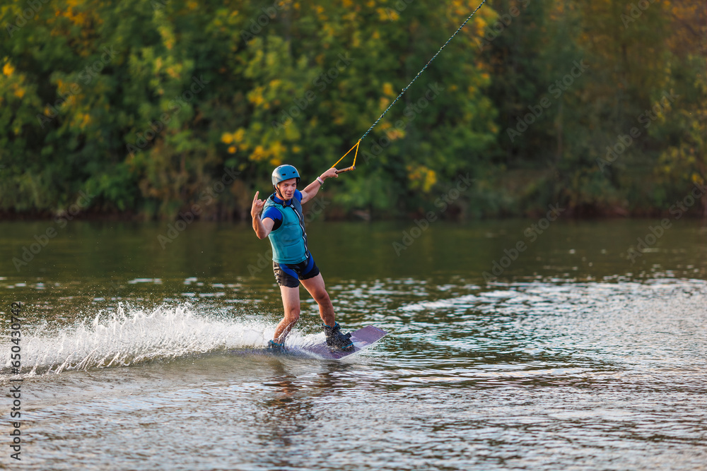 An athlete performs a trick on the water. Park at sunset. Wakeboard rider An athlete performs a trick on the water. Park at sunset. Wakeboard rider