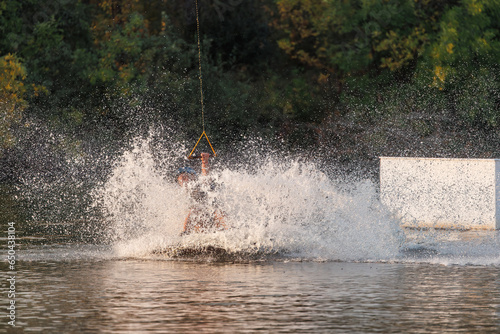 An athlete performs a trick on the water. Park at sunset. Wakeboard rider © WoodHunt
