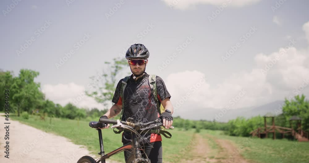 Male mountain biker fully geared portrait. Exploring dirt road in a scenic meadow. Adventure in a picturesque landscape. Male mountain biker fully geared portrait. Exploring dirt road in a scenic meadow. Adventure in a picturesque landscape.