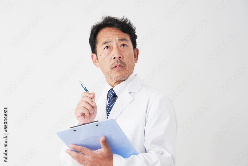 バインダーを使って書類を書く中年の医師 白背景 バインダーを使って書類を書く中年の医師 白背景