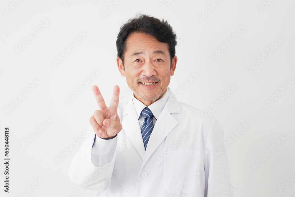 ピースサインをする中年の医師　白背景