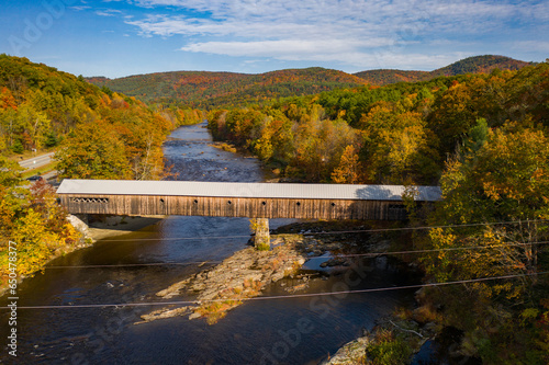 Covered bridge with fall foliage landscape over river in Dummerston, Vermont New England town during autumn season