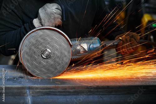Metal plate cutting with abrasive disk and splashing sparks photo