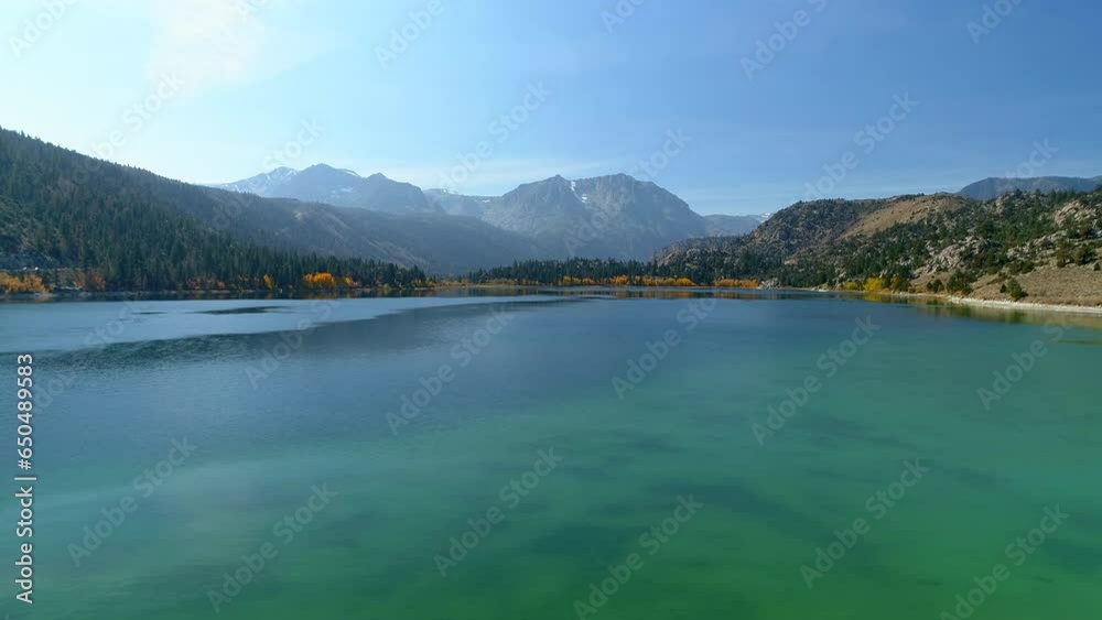 Aerial Panning Shot Of Tranquil Lake By Mountain Against Sky On Sunny Day - Mammoth Lakes, California Aerial Panning Shot Of Tranquil Lake By Mountain Against Sky On Sunny Day - Mammoth Lakes, California