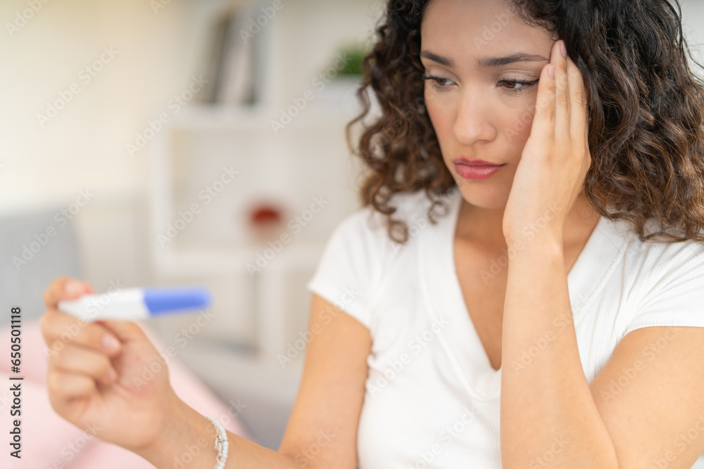 Desolated woman looking at the results of a pregnancy test Desolated woman looking at the results of a pregnancy test