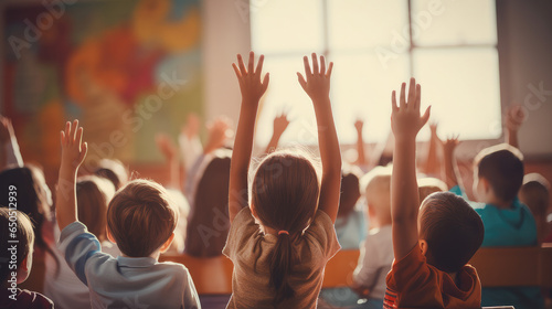 education, elementary school, learning and people concept - group of school kids with teacher sitting in classroom and raising hands. photo