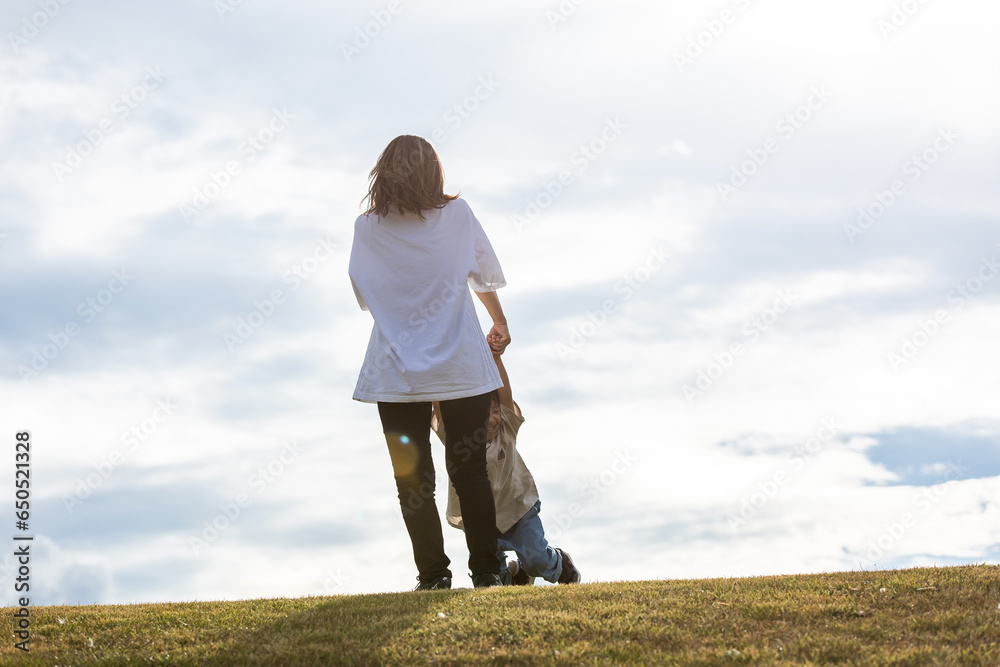 丘の上で手を繋ぐ親子　Parent and child holding hands