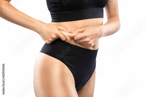 Girl pulls the skin on the abdomen, showing the body fat in the abdominal area and sides. Treatment and disposal of excess weight, the deposition of subcutaneous fat.