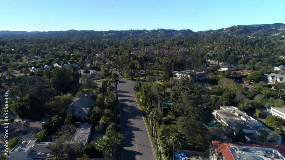 Aerial Forward Shot Of Vehicles On Road Intersection Amidst Houses In Neighborhood Against Blue Sky - Los Angeles, California