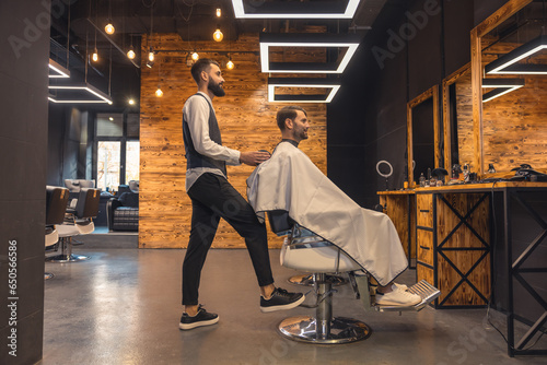 Man getting new trendy haircut or hairstyle with professional male barber.