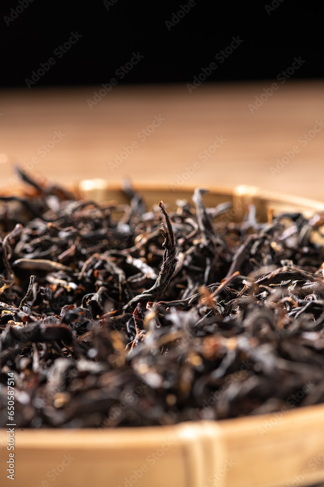 Dried Chinese tea leaves, oriental food culture, dark background indoors, wooden tabletop