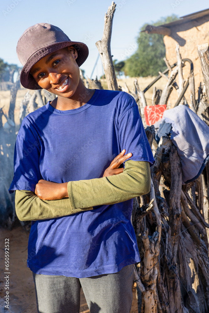 smiling african teenager in the village posing with crossed arms in front of the outdoors kitchen in the yard smiling african teenager in the village posing with crossed arms in front of the outdoors kitchen in the yard