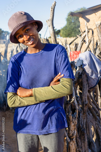 smiling african teenager in the village posing with crossed arms in front of the outdoors kitchen in the yard