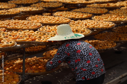 Photography Fresh picked Persimmon fruit in baskets laid out in the sun to ripen with a woma
