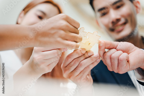Closeup image of a group of people holding and putting a piece of white jigsaw puzzle together,A business group wishing to bring together the puzzle pieces