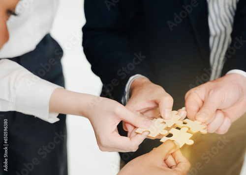 Closeup image of a group of people holding and putting a piece of white jigsaw puzzle together,A business group wishing to bring together the puzzle pieces