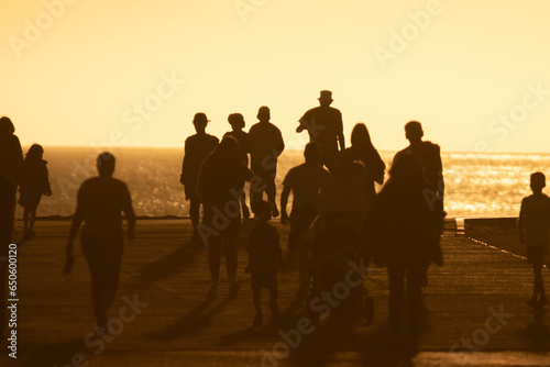 Silhouettes of people walking at yellow bright sunset © KONSTANTIN SHISHKIN