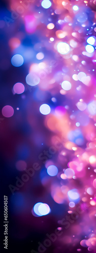 A purple bokeh background made of circular lights in shades of pink, blue, and purple. The background is dark, which makes the lights stand out. Soft, dreamy and festive mood.