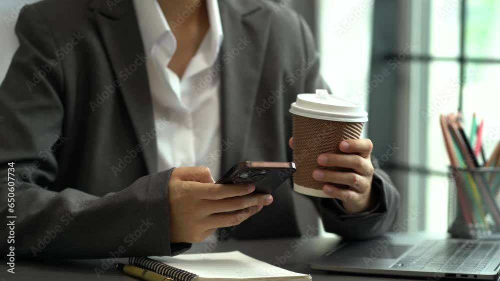 Women are using a mobile phone wifi connection on the desk with a cup of coffee in the morning. Women are using a mobile phone wifi connection on the desk with a cup of coffee in the morning.