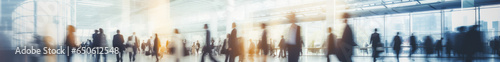 Blurred business people walking at a trade fair  conference or walking in a modern hall or airport  motion speed blur  wide panoramic banner.