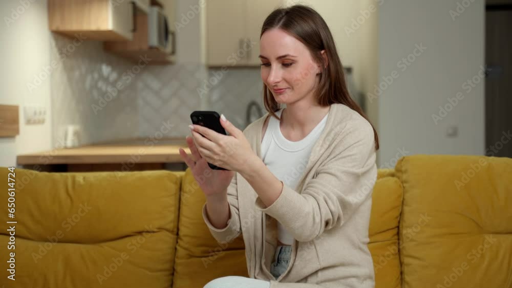 The girl communicates, makes electronic purchases on the Internet, uses social networks, streaming service sitting in the living room on a yellow sofa. The girl communicates, makes electronic purchases on the Internet, uses social networks, streaming service sitting in the living room on a yellow sofa.