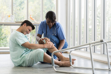 Female nurse caring male patient falling from walker to the floor in patient room at hospital. Accident and Health care concept