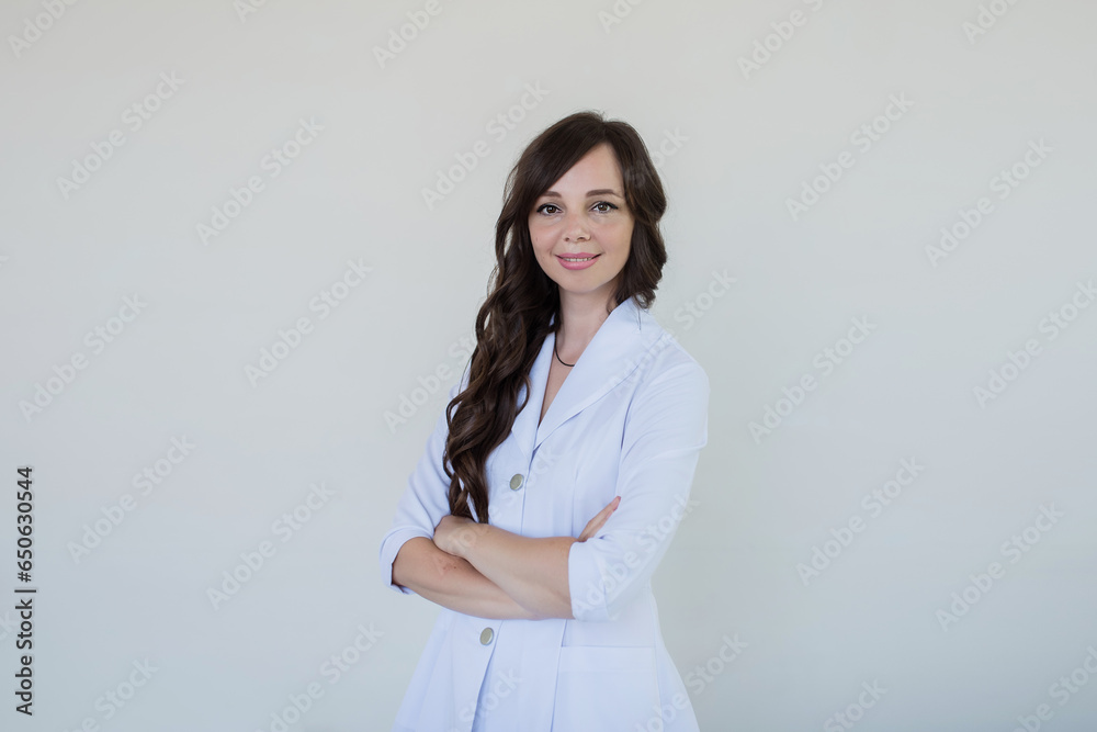 Portrait of a smiling female doctor standing on a gray background, a woman in medical white clothes Portrait of a smiling female doctor standing on a gray background, a woman in medical white clothes