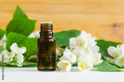 Small bottle with essential oil and mock orange  jasmine  flowers. Aromatherapy  herbal medicine concept. Copy space.