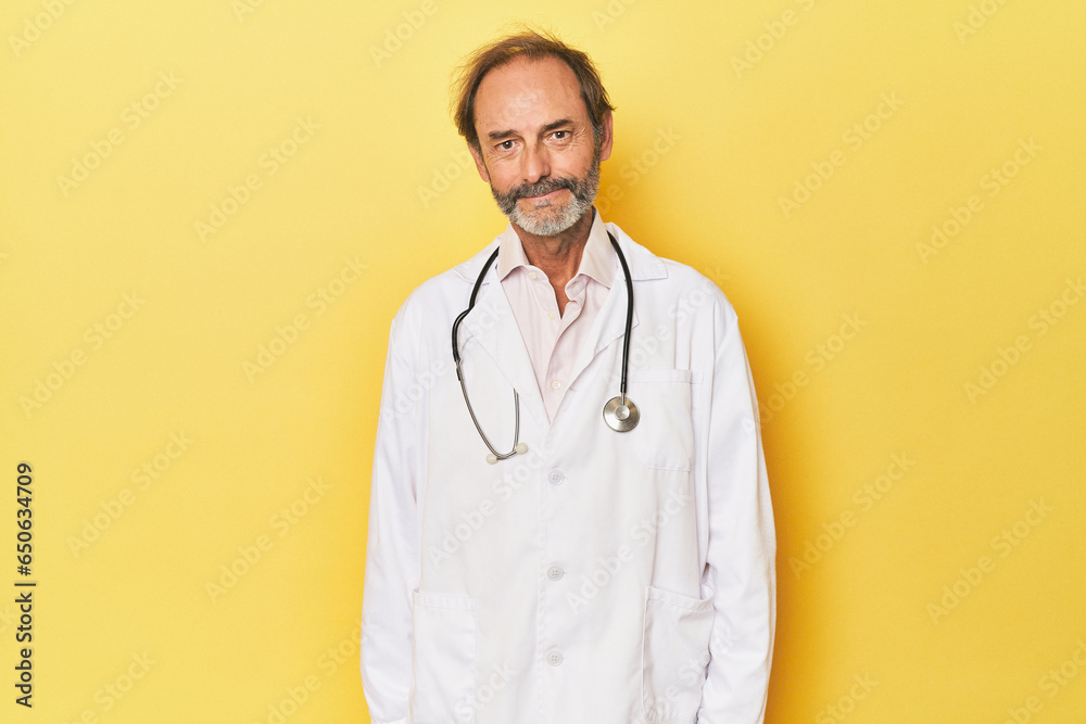 Doctor with stethoscope in yellow studio happy, smiling and cheerful.