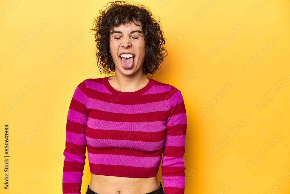 Caucasian curly-haired woman in pink striped-top funny and friendly sticking out tongue. Caucasian curly-haired woman in pink striped-top funny and friendly sticking out tongue.