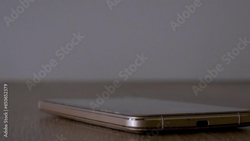 close up teps on a smartphone to destroy the phone illuminated by police lights