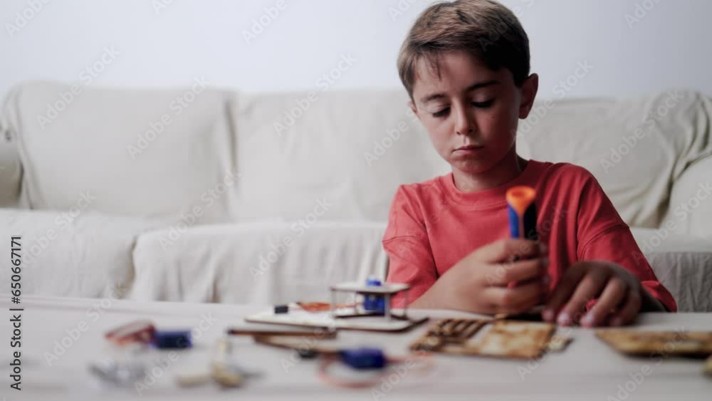 Latino kid building robotic toy machine inside home living room - Homeschool project, STEM science education Latino kid building robotic toy machine inside home living room - Homeschool project, STEM science education