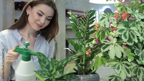 Female florist sprays water on houseplants at flower shop