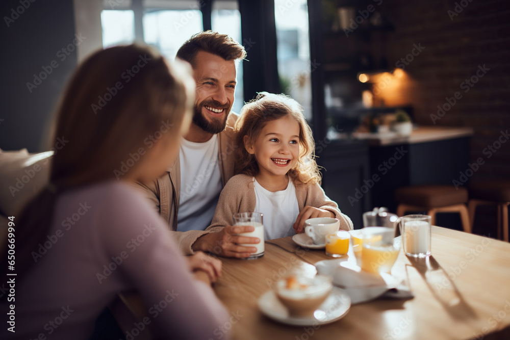 Little girl and parent happily having breakfast in the kitchen - obrazy, fototapety, plakaty 