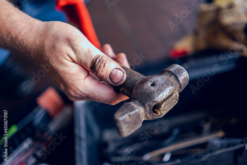 A hammer in the dirty hand of a technician