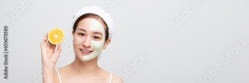 Emotional young woman with facial mask and halves of ripe orange on white background. Web banner.
